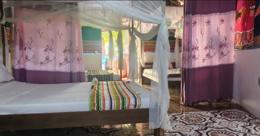 Intérieur du bungalow avec lits, moustiquaires et rideaux